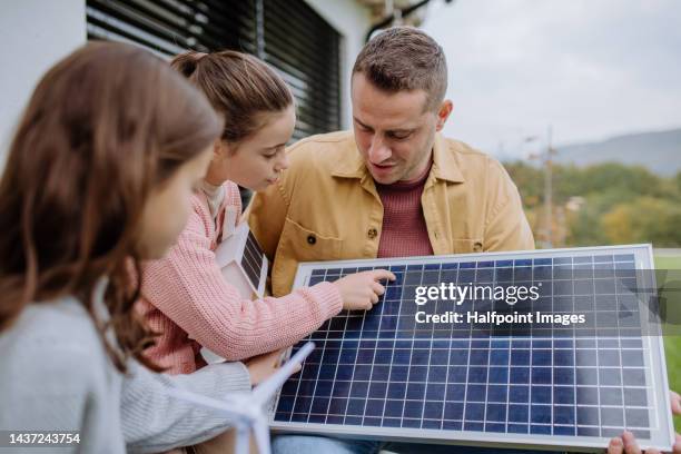 happy girl holding model of house with solar panels. alternative energy, saving resources and sustainable lifestyle concept. - project greenlight stock pictures, royalty-free photos & images