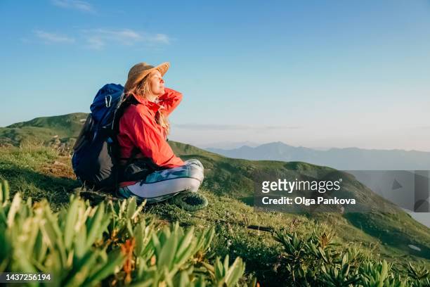 female hiker enjoys picturesque mountain view - discovery bags walking stock-fotos und bilder