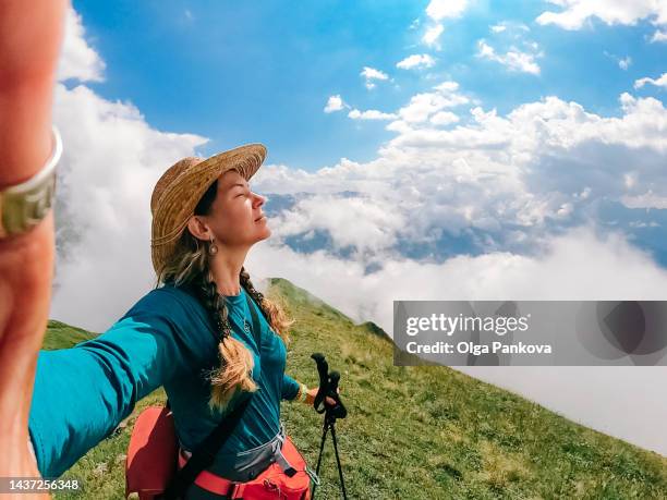 female hiker enjoys mountain view and takes a selfie - walking side view stock-fotos und bilder