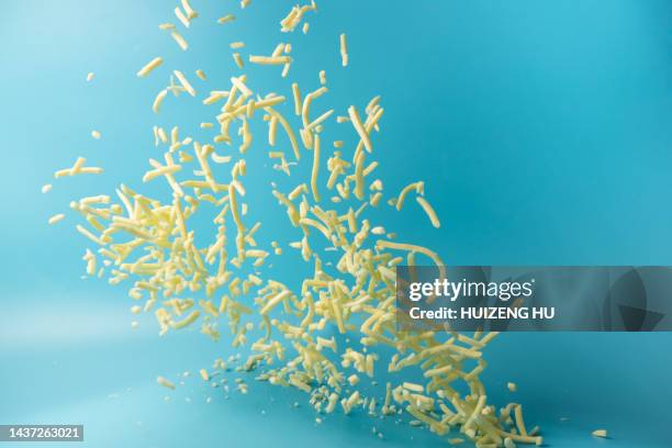 shredded mozzarella cheese flying in air on blue background - grated cheese stock pictures, royalty-free photos & images