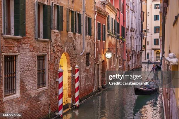 gondolier and customers in a narrow canal on a late afternoon - gondola traditional boat stockfoto's en -beelden