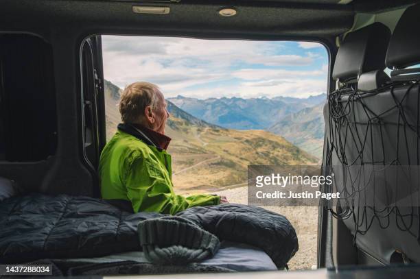 a senior male takes in the view of the mountains from his campervan - french provincial interior stock-fotos und bilder