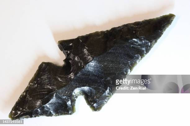 close up of an obsidian arrowhead replica on white background - obsidian stock pictures, royalty-free photos & images