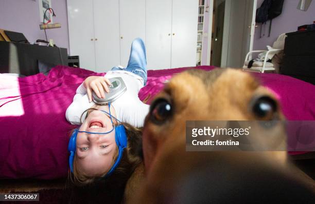 Girl wearing headphones and listening to music with a cd player cuddling her dog