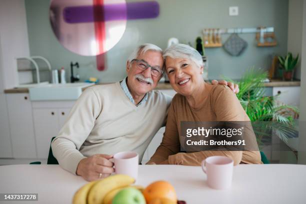 glückliches älteres paar, das sich zu hause entspannt - lebensversicherung stock-fotos und bilder