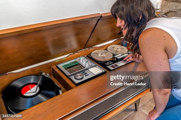 young woman plays an lp record on an outdated mid century hi-fi stereo console wooden furniture - walkman closeup stock pictures, royalty-free photos & images