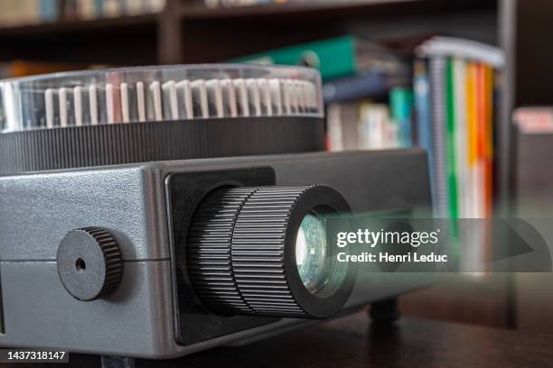 vintage slide projector shining light beam with bookcase background - diaprojektor stock-fotos und bilder