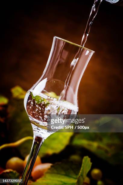 strong alcoholic drink being poured into shot glass,rustic stil - grappa stockfoto's en -beelden