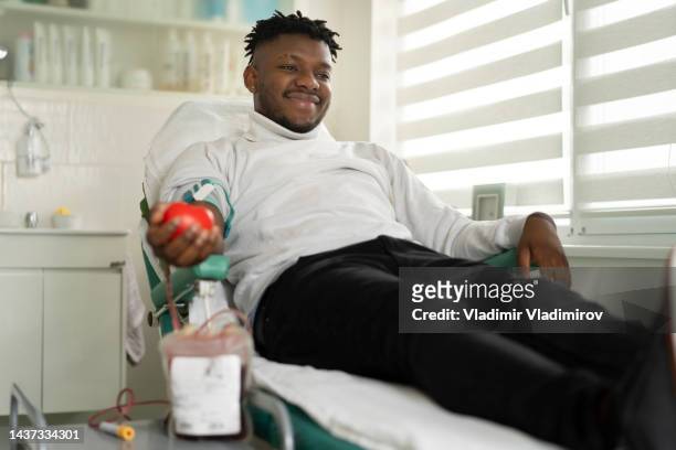 donante de sangre acostado, sonriendo durante la donación de sangre - banco de sangre fotografías e imágenes de stock