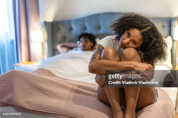 triste jovem mulher sentada enrolada na cama - young black girlfriends - fotografias e filmes do acervo