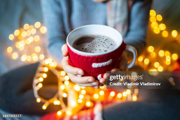 小さなニットジャケットを着た一杯のコーヒーが両手で握られている - coffee christmas ストックフォトと画像