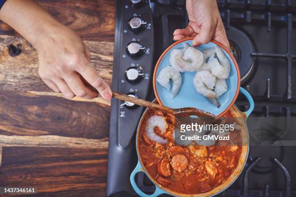 zubereitung cajun stil huhn, garnelen und wurst jambalaya in einem gusseisen topf - cajun food stock-fotos und bilder