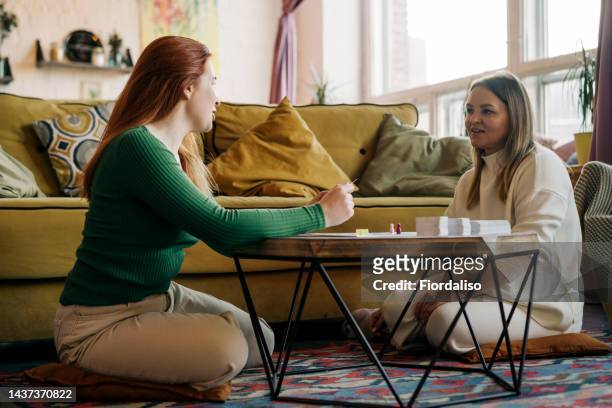 two women are playing board games at the table - game night leisure activity stock pictures, royalty-free photos & images