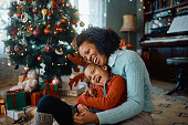 Cheerful African American mother and daughter having fun on Christmas day at home.