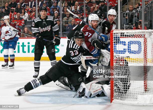 Compher of the Colorado Avalanche crashes the crease against Ryan Graves and Vitek Vanecek of the New Jersey Devils during the third period at the...