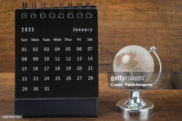 calendar desk 2023: january is the month for the organizer to plan and deadline with a crystal globe against a wooden table background. - desk calendar stock pictures, royalty-free photos & images