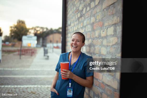 cheerful nurse holding a disposable cup in her hands - coffee break outside stock pictures, royalty-free photos & images