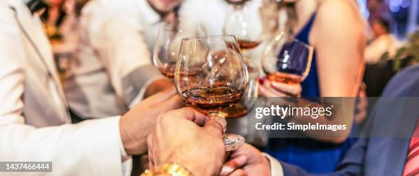 group of friends a toast to the cheers of cognac or brandy. - bourbon whisky stockfoto's en -beelden