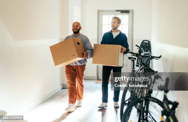 male couple carrying boxes into new home on moving day - man with moving boxes authentic stockfoto's en -beelden