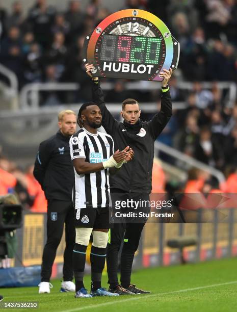 Newcastle player Allan Saint-Maximin waits to come on a substitute as fourth official Ben Toner holds up the rainbow laces board during the Premier...