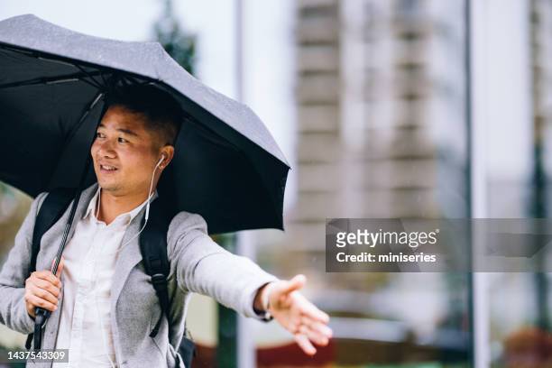smiling businessman usingâ with umbrella hailing a cab in the city - caught in rain stock pictures, royalty-free photos & images
