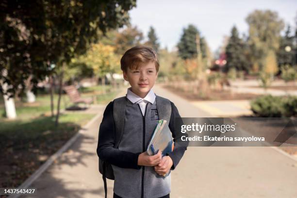 a schoolboy with a school satchel and books at school. the concept of education. back to school. a student goes to class. stylish boy with a backpack. - school boy with bag stock pictures, royalty-free photos & images