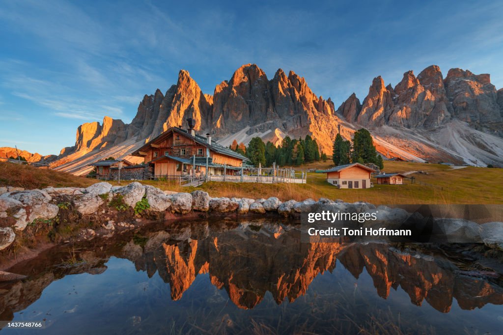 Perfect reflection of the Alpen Glow with a cabin in front of the Geislergruppe