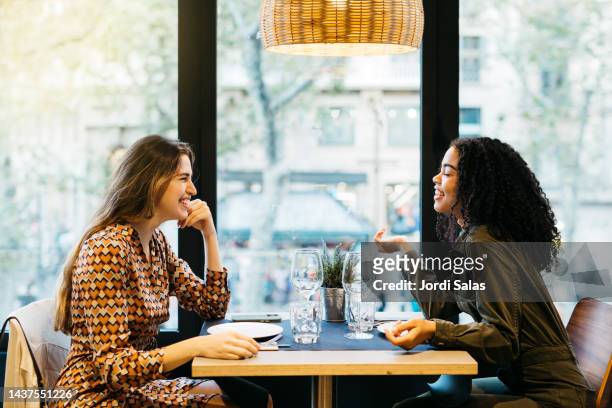 two women sitting on a restaurant - lesbian date - fotografias e filmes do acervo