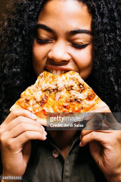 woman biting a slice of a pizza - biting on something stock-fotos und bilder