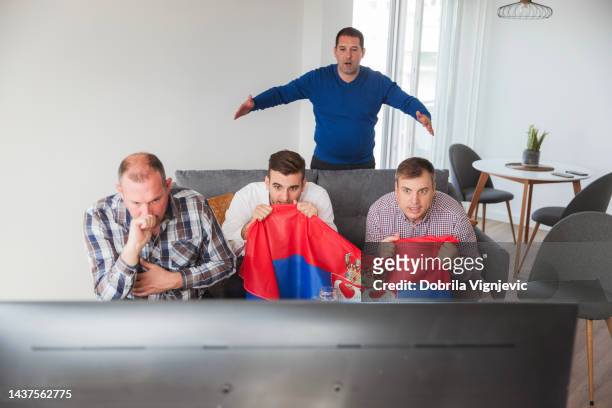nervöse männer halten serbische flagge, wenn sie ein fußballspiel im fernsehen sehen - serbian flag stock-fotos und bilder