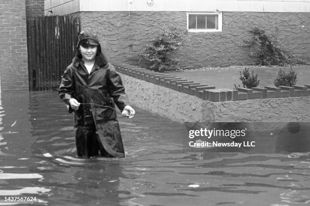 Young man floats a toy boat along Williamson Avenue in East Rockway, New York on September 12, 1960. The streets are flooded from high tides from...