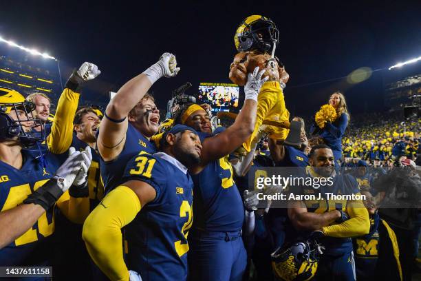 Mike Morris and other players of the Michigan Wolverines celebrate with the Paul Bunyan trophy after winning a college football game against the...
