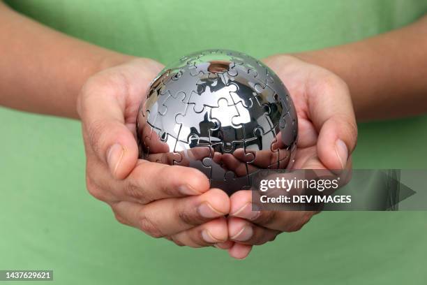 hand holding metal jigsaw puzzle globe - glass map india stock pictures, royalty-free photos & images