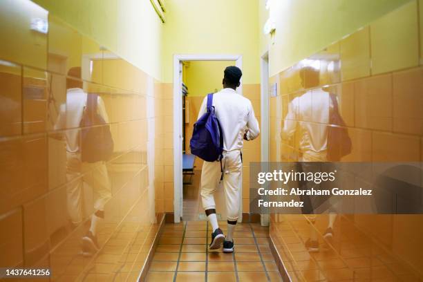 a young fencer walking down the locker room hallway with his backpack - martial arts man stock pictures, royalty-free photos & images