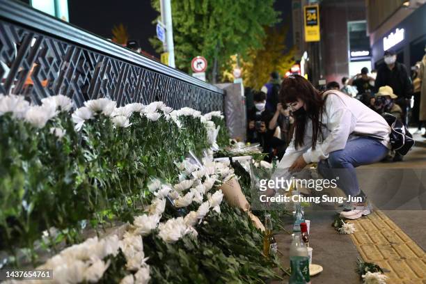 Woman lays flowers as she mourns at the street of a deadly stampede during a Halloween festival on October 30, 2022 in Seoul, South Korea. 151 people...