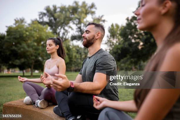 three people meditating outdoors - mindfulness stock pictures, royalty-free photos & images