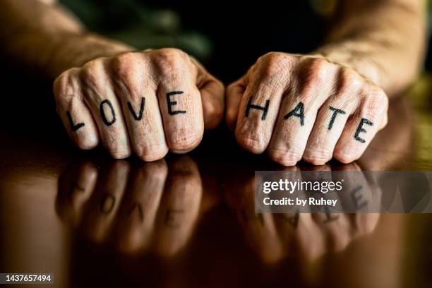 close-up of a man's fists with the words love and hate written on his fingers as a tattoo. - love hate stock-fotos und bilder