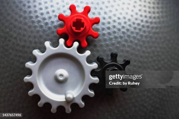 group of coloured gears linked to each other on a metallic-looking background - engineer gearwheel factory stock pictures, royalty-free photos & images