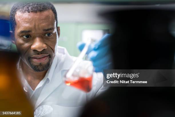 toxicity and hazardous waste testing in environmental issues. male african american scientists hold toxicity and hazardous waste testing on a conical flask in an environmental laboratory. - specimen holder stock pictures, royalty-free photos & images