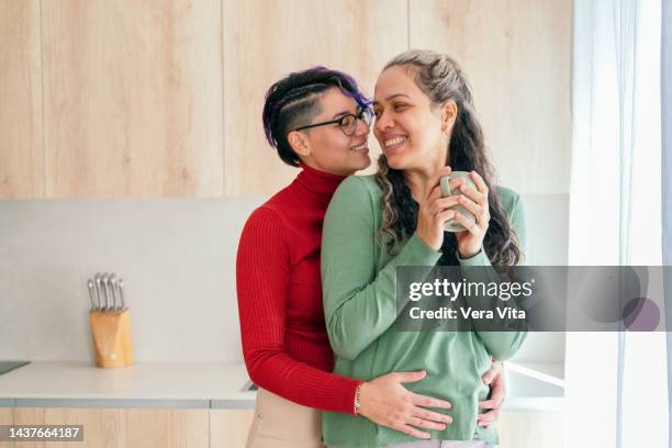 latin american gay couple in love kissing and drinking coffee indoors. - images of lesbians kissing stock pictures, royalty-free photos & images