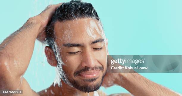 shower, cleaning and hygiene with a man washing his face or hair in studio on a blue background for haircare. shampoo, soap and water with a handsome male grooming his wet head to clean or stay fresh - washing hair stock pictures, royalty-free photos & images