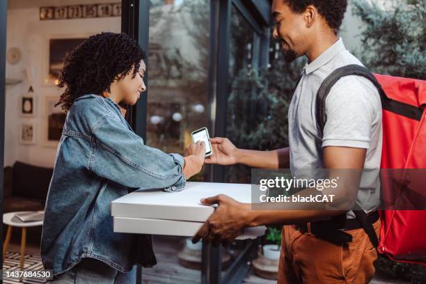 young woman signing for the delivery - pizza delivery stock pictures, royalty-free photos & images