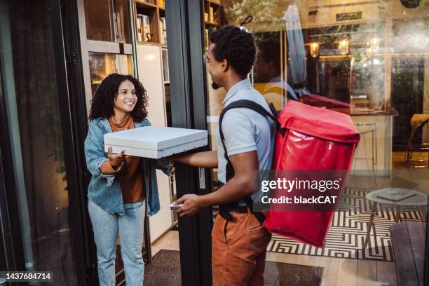 pizza delivery man giving pizza to a woman - pizza delivery stock pictures, royalty-free photos & images