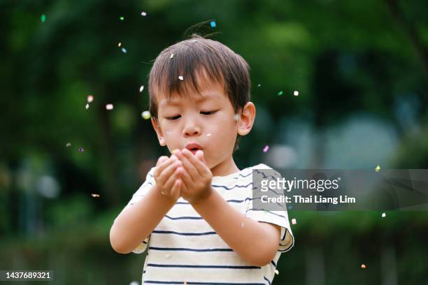 porträt eines glücklichen asiatischen jungen, der konfetti im hinterhof bläst - 2 people back asian stock-fotos und bilder