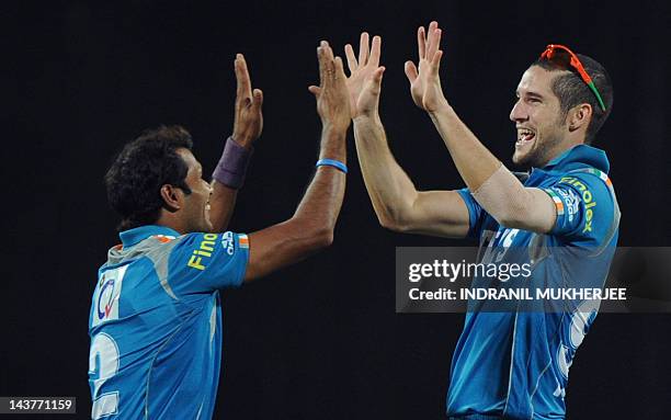 Pune Warriors India cricketers Ashok Dinda and Wayne Parnell celebrate the dismissal of unseen Mumbai Indians batsman Harbhajan Singh during the IPL...