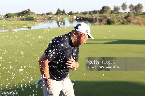 Jordan Smith of England is sprayed with champagne by Matthew Southgate of England on the 18th green after winning the Portugal Masters during Day...