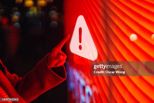 close-up of  female hand touching illuminated digital screen displaying a warning sign - warning signs bildbanksfoton och bilder