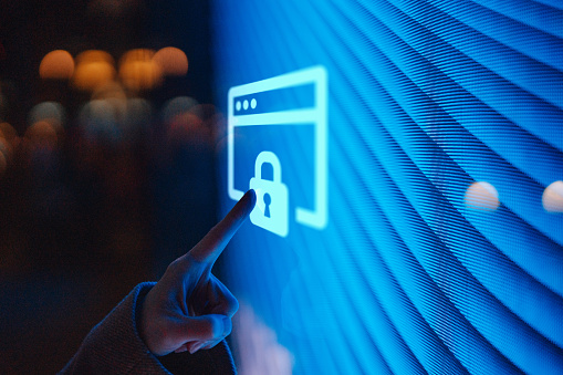 Close-up of female hand touching illuminated digital screen displaying a locked sign