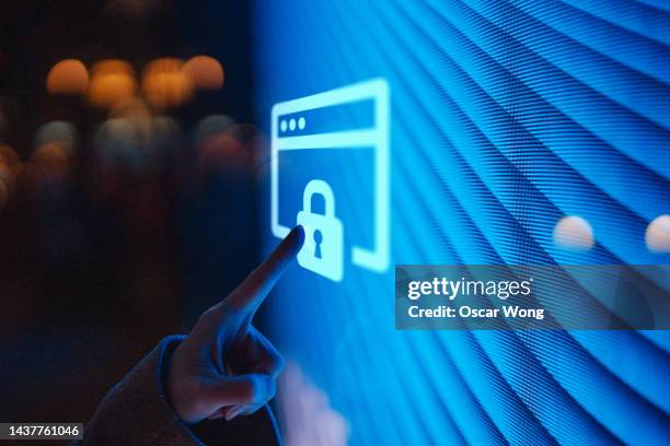 close-up of  female hand touching illuminated digital screen displaying a locked sign - cybersecurity - fotografias e filmes do acervo