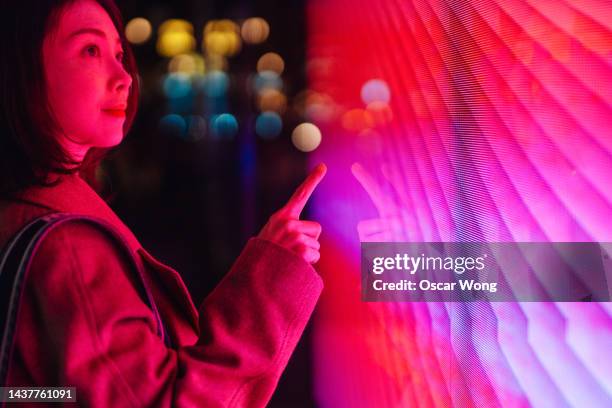 young asian woman touching illuminated digital screen - rosa color fotografías e imágenes de stock